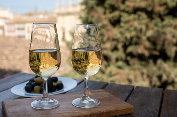 Γευστική δοκιμή ισπανικού γλυκού και ξηρού οχυρωμένου οίνου Vino de Jerez sherry και ελιάς με θέα στις στέγες και τα σπίτια της παλιάς ανδαλουσιανής πόλης, νότια της Ισπανίας - Φωτογραφία, εικόνα