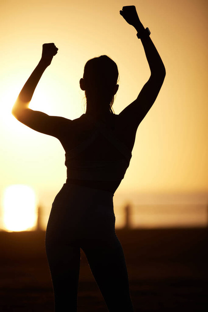 Stay hopeful about every new day. Silhouetted shot of a woman cheering outdoors - Photo, Image