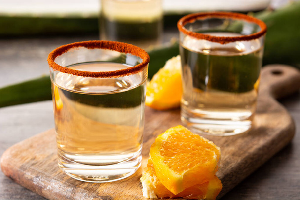 Mexikanisches Mezcal-Getränk mit Orangenscheiben und Wurmsalz auf Holztisch - Foto, Bild