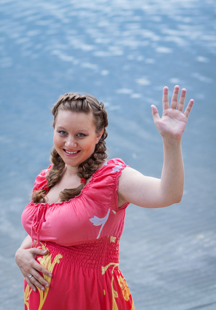 Беременная женщина машет рукой. Концепция материнства и женственности
 - Фото, изображение