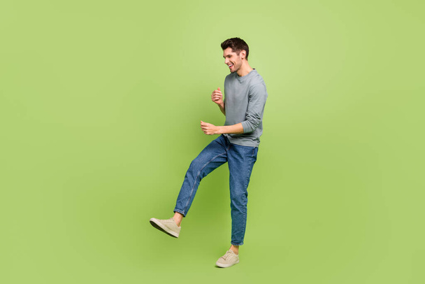 Full body profile side photo of good mood delighted male enjoy dancing in club isolated on green color background. - Fotoğraf, Görsel