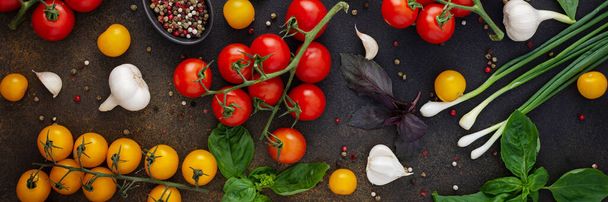 Yiyecek afişi, taze olgun kırmızı ve sarı domatesler, baharatlar ve fesleğen yaprakları, sarımsak ve yeşil soğanlar koyu bir tahta üzerinde, sağlıklı gıda kavramı, üst görünüm - Fotoğraf, Görsel