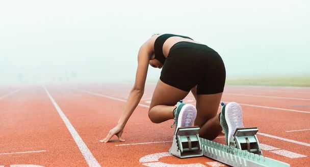 Shes race ready. Rearview shot of an unrecognizable young sportswoman taking her mark on starting blocks - Foto, afbeelding
