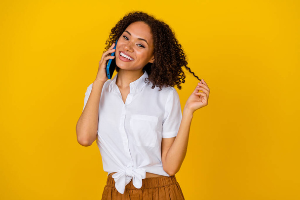 Portrait of gorgeous positive lady speak telephone hand ply hairdo curl isolated on yellow color background. - Фото, изображение