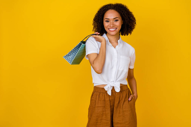 Portrait of adorable positive person arm hold small boutique bag beaming smile isolated on yellow color background. - Foto, afbeelding