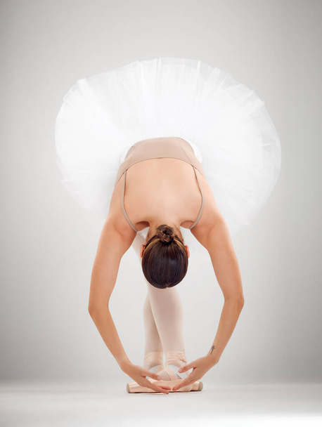 And scene. Full length shot of an attractive young female ballet dancer in studio against a grey background - Fotó, kép