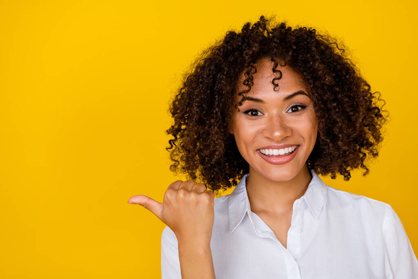 Portrait of charming cheerful lady indicate thumb finger empty space isolated on yellow color background. - Foto, Imagem