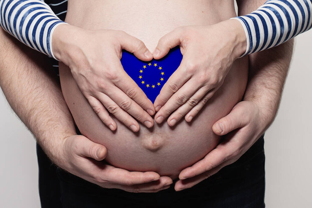 European family concept. Man embracing pregnant woman belly and heart with European Union flag colors closeup - Foto, afbeelding