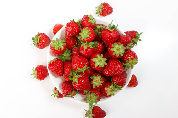 Red ripe strawberry in the white bowl, light background - Foto, afbeelding
