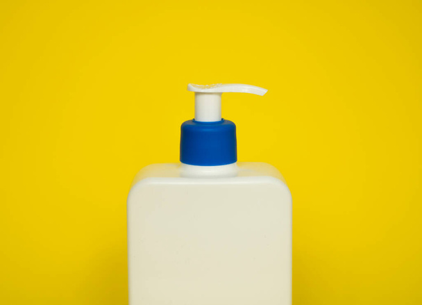 White plastic soap or shampoo dispenser pump bottle isolated on blue background. Skin care lotion. Bathing essential product. Shampoo bottle. Bath and body lotion. Fine liquid hand wash - Foto, Imagem