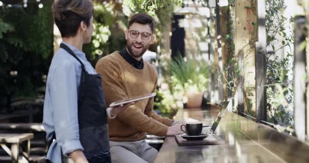 4k відеозапис молодого чоловіка, який отримує каву, використовуючи свій ноутбук у кафе
. - Кадри, відео