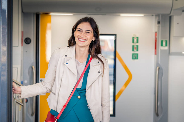 Potrait of beautiful traveler woman getting off the train smiling - Fiatal üzletasszony kukucskál ki a vonat ajtaján keres valakit - Fotó, kép