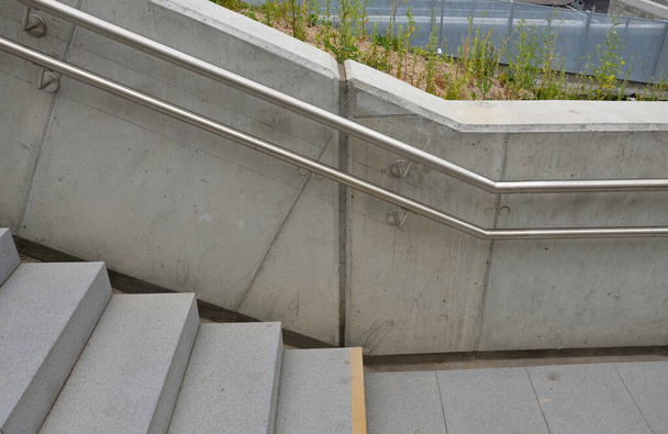 a staircase with concrete sides at a public building. the safe staircase has two handrails, one with a reduced height for children under 12 at the entrance to the school - Fotografie, Obrázek