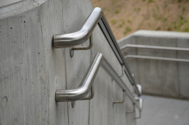 a staircase with concrete sides at a public building. the safe staircase has two handrails, one with a reduced height for children under 12 at the entrance to the school - Photo, Image