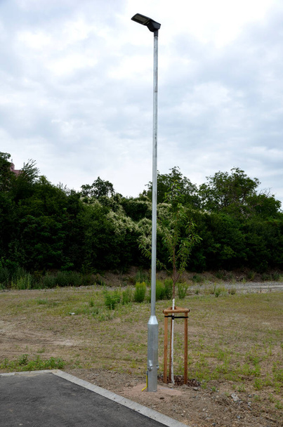 straatlamp bij de stoep of op het perron met een kantelbare mast. de gegalvaniseerde buis van de lamp heeft een scharnier in het onderste deel dat u toelaat om mast buigen naar de grond en het uitvoeren van onderhoud - Foto, afbeelding