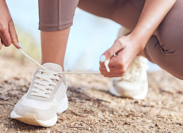 I have goals to accomplish today. Closeup shot of an unrecognisable woman tying her shoelaces while exercising outdoors - Photo, Image