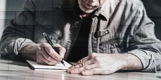 Reifer Mann macht sich Notizen auf einem Notizbuch, geometrisches Muster - Foto, Bild