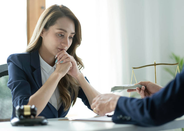 A professional asian female lawyer or business legal consultant having a secret meeting with her client and receives a bribe. cropped sho - 写真・画像