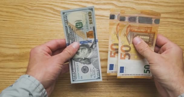 Exchange one hundred dollars for one hundred euros. Exchange rate has equalized. Male hands hold cash money in their hands, top view. High quality 4k footage - Πλάνα, βίντεο