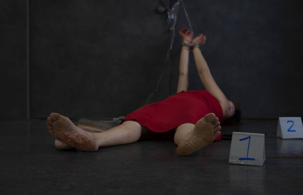 woman blood body in red dress lying on the floor being tied (selective focus)and beside is scene area marked sign witness.concept violence,victim,crime,murder - Photo, image