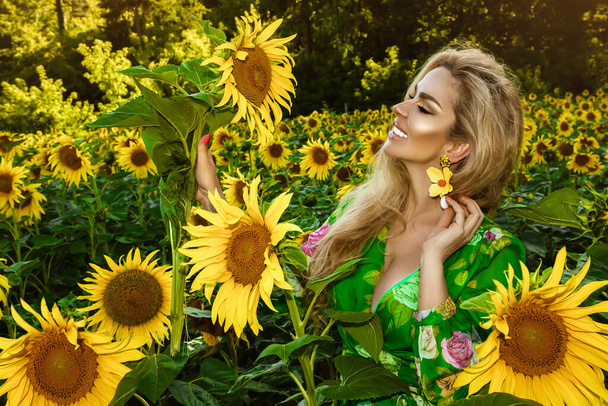 Beautiful young woman in a field of sunflowers. Happy female model is holding sunflower in Sunflowers field. Natural beauty. - 写真・画像