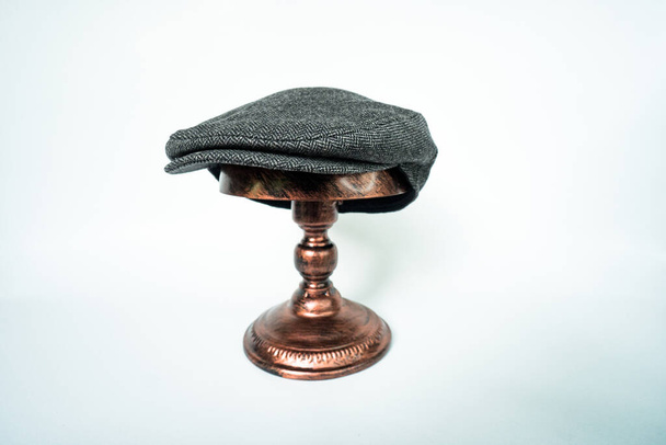 Detail of scally or flat cap in midnight-dark-black herringbone tweed fabric set on a bronze head mannequin on a white background - Photo, image