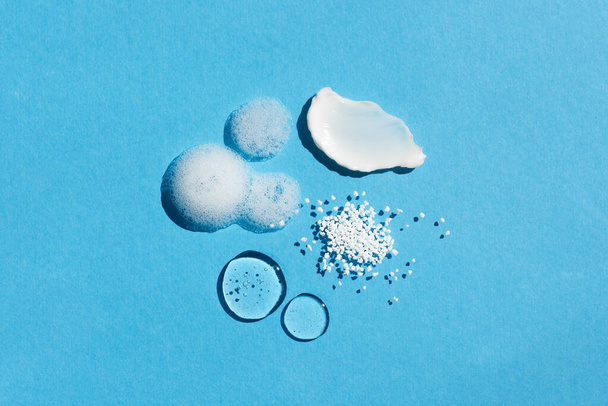 Close up cosmetic swatch and drops. Appearance of the texture of the cream, gel, foam and granules on a blue background. Natural skincare products. Beauty concept for face and body care - Photo, image