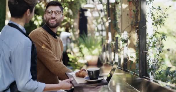 4k videomateriaalia nuori mies saa tarjoillaan kahvia, kun käytät hänen kannettava kahvilassa. - Materiaali, video