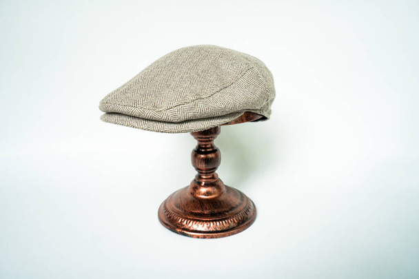 Detail of scally or flat cap in dark brown pattern  herringbone tweed fabric set on a bronze head mannequin on a white background - Photo, Image