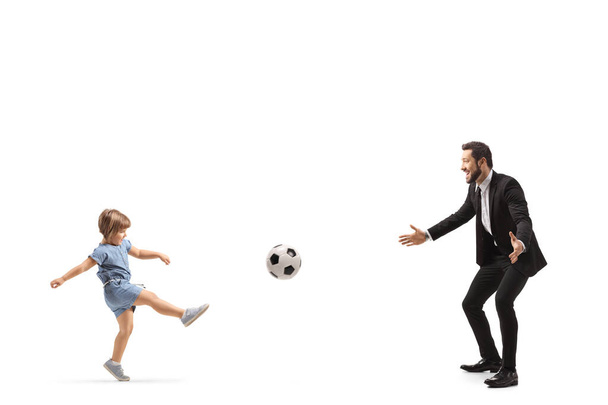 Full length profile shot of a little girl playing a football with her father isolated on white background - Foto, imagen
