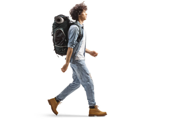 Full length profile of a young male traveler walking with a backpack isolated on white background - Foto, imagen