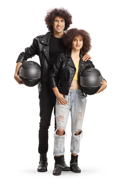 Full length portrait of a young man and woman in leather jackets holding motorbike helmets isolated on white background - Φωτογραφία, εικόνα