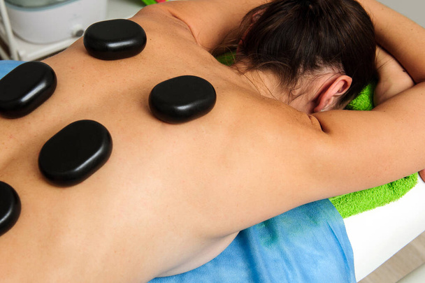 Vista de perto do massagista masculino massageando costas e omoplatas da fêmea deitada na mesa de massagem no salão de spa. Mulher bonita com pele perfeita recebendo massagem relaxante. - Foto, Imagem