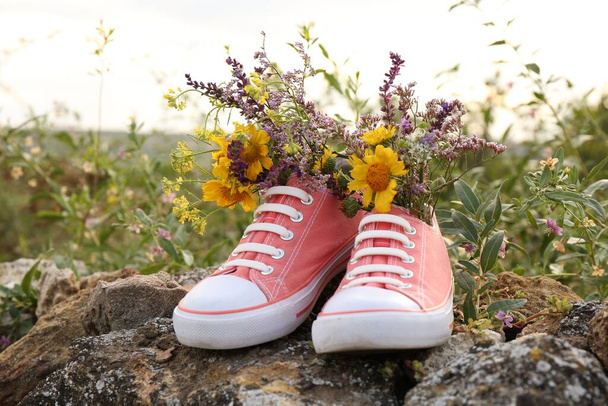 Shoes with beautiful flowers on stones outdoors - Фото, изображение