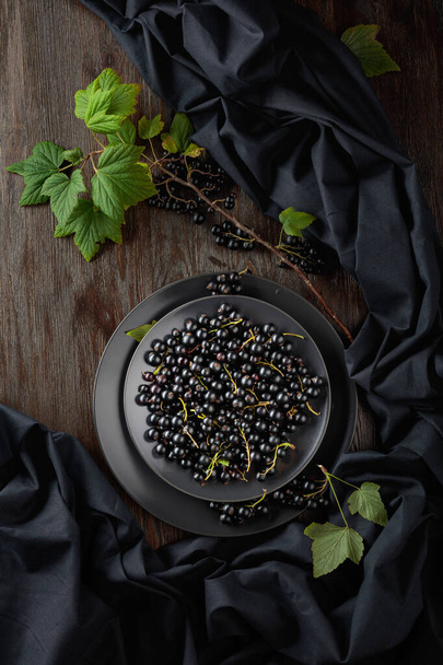 Black currant with leaves on a old wooden table. Top view. - Photo, Image