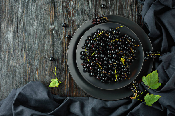 Black currant with leaves on a old wooden table. Top view. - Foto, immagini