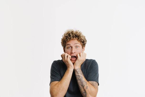 Young curly man expressing surprise and screaming at camera isolated over white wall - Фото, зображення