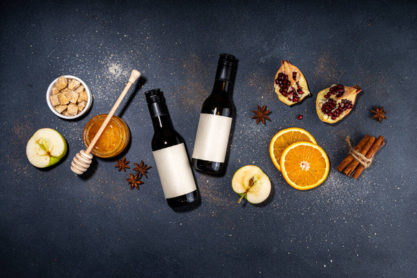 Different mulled wine ingredients set on black background, flat lay with wine bottle, cinnamon, apple, orange, anise star, simple autumn food drink cooking background - Foto, Bild