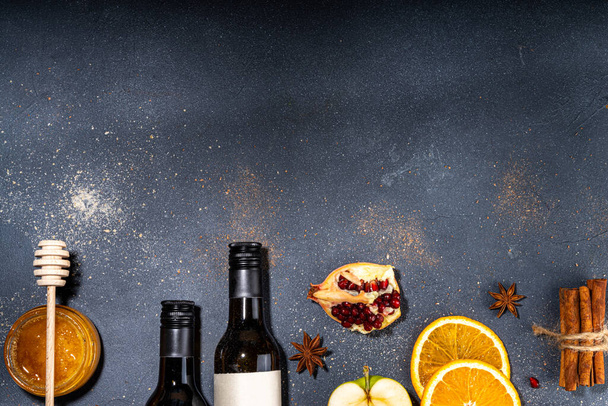 Różne grzane składniki wina ustawione na czarnym tle, płaskie leżały z butelką wina, cynamon, jabłko, pomarańcza, gwiazda anyżu, proste tło gotowania jesienią żywności - Zdjęcie, obraz