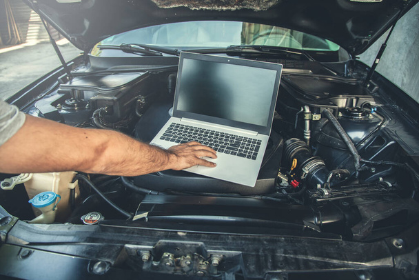 man to repair car with hand computer - Foto, imagen