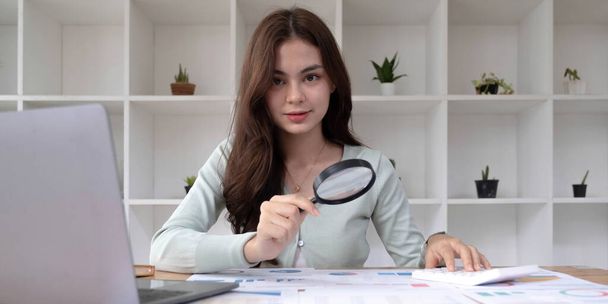 Tax inspector and financial auditor looking through magnifying glass, inspecting company financial papers, documents and report - Photo, Image
