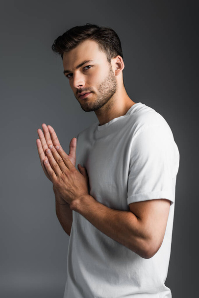 Portrait of young man in white t-shirt isolated on grey  - 写真・画像