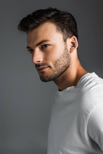 Portrait of brunette man in white t-shirt looking away isolated on grey  - Foto, Bild