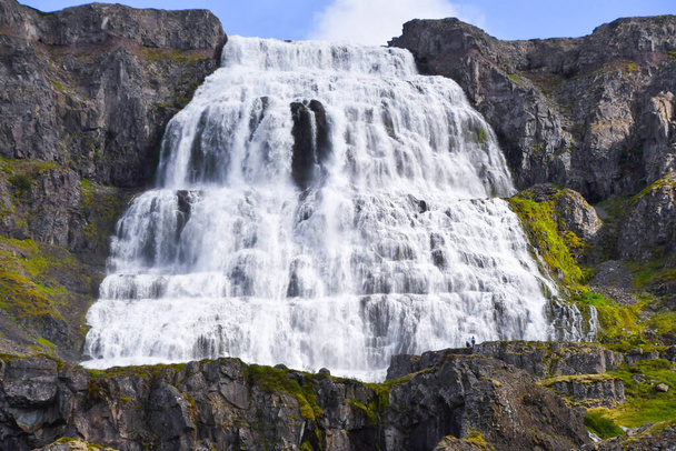 Zwei Personen vor dem sehr hohen und erstaunlichen Wasserfall im Nordwesten Islands - Foto, Bild