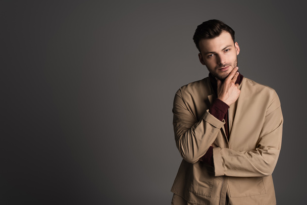 Stylish young man in brown jacket looking at camera isolated on grey  - Foto, Imagem