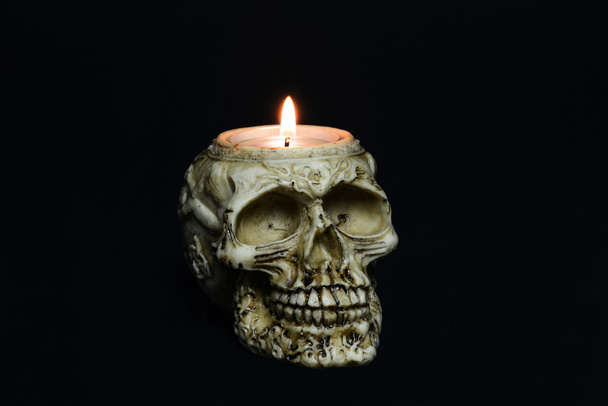 Creepy skull candle on black background - half turn - 写真・画像