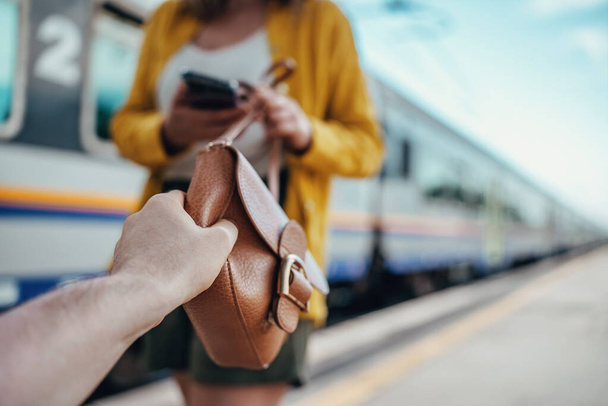 Thief robs a woman's handbag at the train station. - Фото, изображение