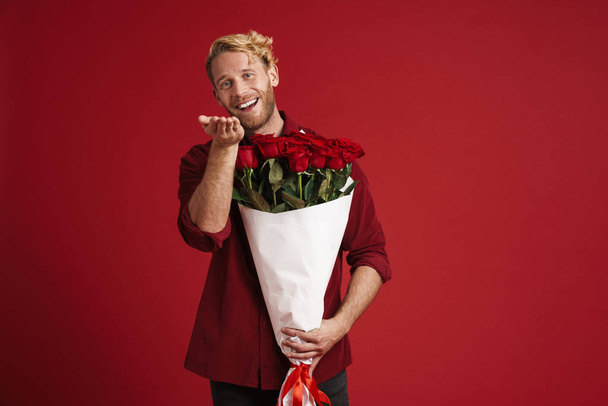 White bearded man smiling while posing with roses isolated over red wall - Φωτογραφία, εικόνα