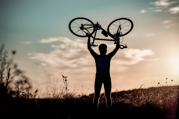 ciclista silhoutte con bicicleta elevada al cielo carrera y concepto de victoria - Foto, imagen