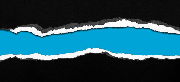 Ripped black paper on blue background, space for copy - Photo, Image